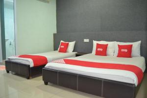 セリ・マンジュンにあるOYO 89737 Hotel Tishoaの赤い枕付きのベッド2台が備わる客室です。