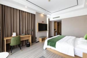 a bedroom with a bed and a desk and a television at GreenTree Inn Zhoushan New Town Hotel in Zhoushan