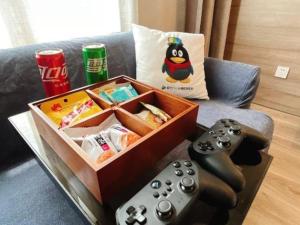 eine Kiste und zwei Videospiel-Controller auf einem Sofa in der Unterkunft Metropolo Hotel Suzhou Guogou Plaza Huaxia in Suzhou