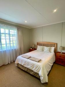 a bedroom with a bed with white sheets and a window at Galil Farm in Crossroads