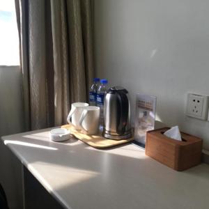 ShenzhenHanting Hotel Shenzhen Baoan Xixiang Taoyuanju的一个带咖啡壶的柜台和一盒水
