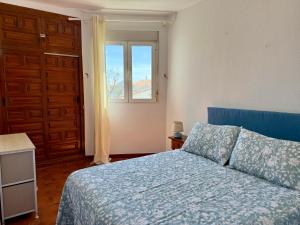 Un dormitorio con una cama con edredón azul y una ventana. en Palmeras 15, en Nerja