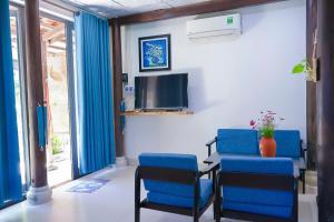 a waiting room with blue chairs and a tv at Dragon Sea Homestay in Hoi An