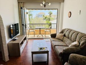 Una sala de estar con un sofá y un televisor de pantalla plana. en Palmeras 15, en Nerja