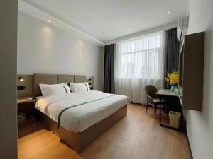 una camera d'albergo con un letto grande e una scrivania di GreenTree Inn Hefei East Wangjiang Road CTCE Express Hotel a Hefei Altre 213 foto