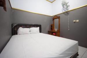 a bedroom with a white bed with a fan at SPOT ON 93620 Anisa Homestay Syariah in Tulungagung