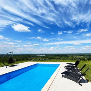 a swimming pool with two chairs and a blue sky at Eagle's View Villa in Batina