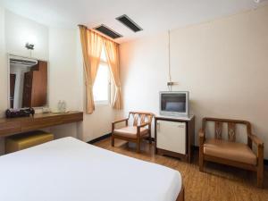 a bedroom with a bed and a tv and two chairs at Muangphol Mansion in Bangkok