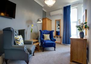 a living room with two blue chairs and a tv at Tyndale B&B Torquay in Torquay