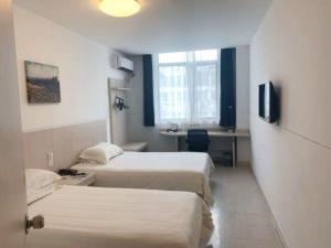 Una habitación de hotel con dos camas y un escritorio. en Jinjiang Inn Central Changshu Yushan, en Changshu 144 fotos más
