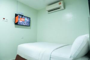 a room with a bed and a tv on the wall at Hotel Sunsurya in Kampong Batu Belah