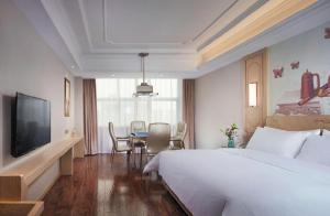 una camera d'albergo con un letto, un tavolo e una televisione di Vienna International Hotel Wuxi Taihu Expo Center a Wuxi