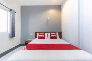 a bedroom with a large bed with red and white pillows at Capital O 75412 V Resort in Ban Wang Ton
