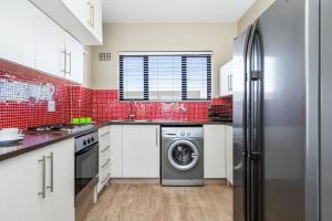 a kitchen with a washing machine and red tiles at Witsand 102 by Host Agents in Bloubergstrand