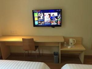 Cette chambre dispose d'un bureau et d'une télévision murale. dans l'établissement 7 Days Inn Tongren Jiangkou Fanjing Mountain National Park, à T'ung-jen