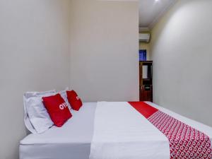 a bed with red and white pillows on it at OYO 90927 Homestay Tentrem 2 in Pati