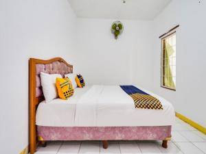 a bedroom with a bed with yellow and black pillows at OYO 91546 Dewi Sudirman Homestay in Bandung