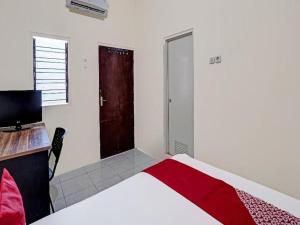 a bedroom with a bed and a desk and a door at Hotel O Wonoayu Residence Syariah in Sidoarjo