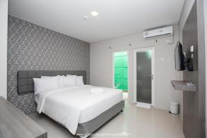 a bedroom with a white bed and a television at Smart Budget Hotel in Stasiun Tawang