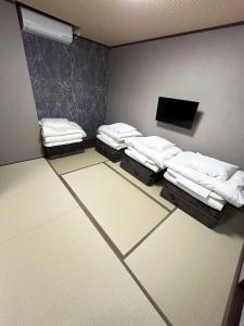 a room with three beds and a flat screen tv at ゲストハウス長浜 グループ旅行や家族旅行カップルでのご利用におすすめです in Nagahama