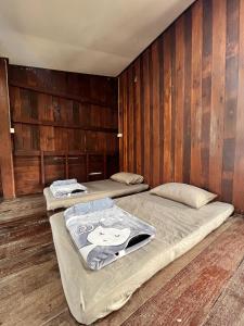 two beds in a room with wooden walls at The Say Ba Homestay at Mae Chaem เด๊อะเซ่บะ โฮมสเตย์ แม่แจ่ม in Mae Chaem