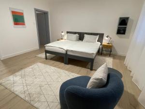 ein Schlafzimmer mit einem Bett und einem blauen Stuhl in der Unterkunft HausKaiser in Wulkaprodersdorf + 4 Fotos