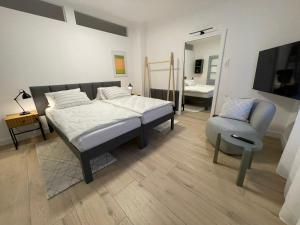 ein Schlafzimmer mit einem Bett, einem Stuhl und einem Spiegel in der Unterkunft HausKaiser in Wulkaprodersdorf