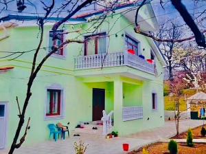 a green and white house with a balcony at Vila Bashllari in Zvarisht