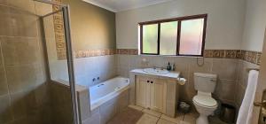 a bathroom with a toilet and a tub and a sink at Robin Cottage Da Gama Lake in White River