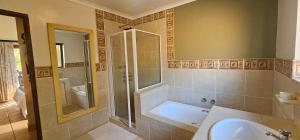 a bathroom with a shower and a tub and a sink at Robin Cottage Da Gama Lake in White River +12 photos