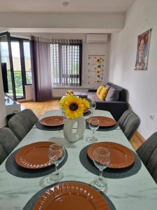 a table with glasses and a vase with a sunflower on it at Sunflower City Center with free garage in Skopje