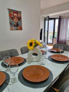 a table with plates and glasses and a vase with a sunflower at Sunflower City Center with free garage in Skopje +20 photos