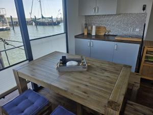 a kitchen with a wooden table with a view of the water at Hausboot Tollow in Stralsund