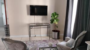 sala de estar con TV, sillas y mesa en Faerie Glen B&B, en Pretoria