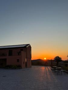 a sunset behind a building with tables and chairs at Il Tramonto - Deluxe Apartments in Roncofreddo