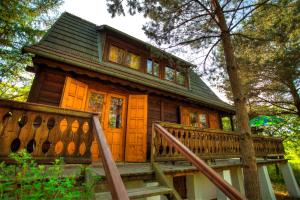 a wooden cabin in the woods with a large porch at Dom z Bali Paweł nad jeziorem Tajty in Giżycko