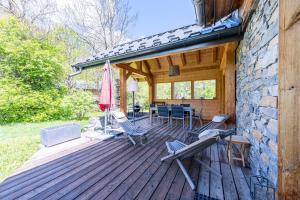 una terraza de madera con sillas y sombrilla en Chalet de l'alpette, en Valloire