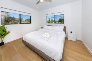 Un dormitorio con una cama blanca con dos ventanas. en Modern 2BR Back House w/ TVs & Full Kitchen, en Los Ángeles