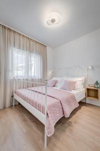 a white bed in a white bedroom with a window at Apartman Sea in Podstrana