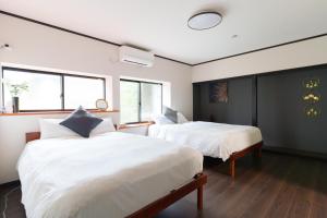 ein Schlafzimmer mit zwei Betten und zwei Fenstern in der Unterkunft Habitacion Cottage Jin in Azagawa