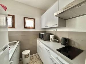 eine kleine Küche mit weißen Schränken und einer Spüle in der Unterkunft Studio Résidence de La Mer L'ILE-ROUSSE in LʼÎle-Rousse