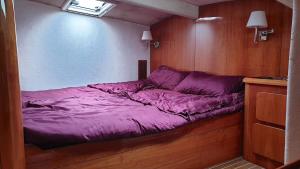 a small bed in a room with purple sheets at ALL ONE Catamaran in Ponta Delgada
