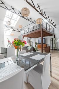 a dining room with a glass table and white chairs at Le Faubourg Saint Martin Loft and Spa 1 in Senlis