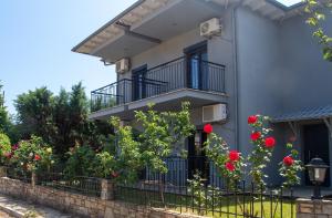 a house with a fence and red roses at Aliston Hotel Thassos in Skala Potamias