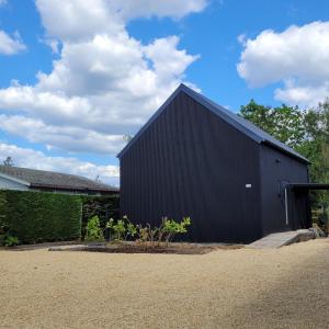 a black building with a black roof at Vakantiewoning aan het water, vissen, wandelen en genieten in de natuur in Geel