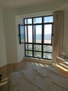a bedroom with a large window with a view of the ocean at Buarcos&Sea Accommodation - Cristal Mar - Your Panoramic Ocean View Retreat in Figueira da Foz +16 photos