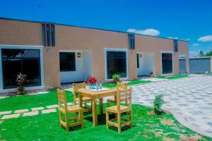 a wooden table and chairs in front of a house at Nico Garden Apartment in Dodoma