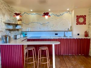 a kitchen with a counter with stools and a table at Maison as Cambous in Sauveterre-la-Lémance +15 photos