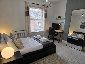 ein Schlafzimmer mit einem Bett, einem Schreibtisch und einem Spiegel in der Unterkunft Bright and Cosy 2 bed House with free parking near the city centre in Central Station