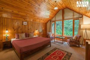 ein Schlafzimmer mit einem Bett in einem Zimmer mit Holzwänden in der Unterkunft StayVista at Retreat Cottages with Lawn, Bonfire in Manali